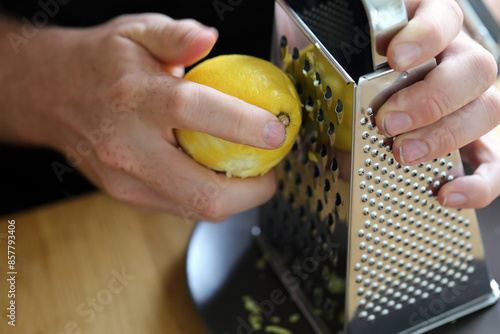 A white man grating lemon zest with a grater. Preparing food. Refreshing ingredients for cooking and baking. Closeup color image of the lemon, grater and the hand of the man. Healthy lifestyle image. photo