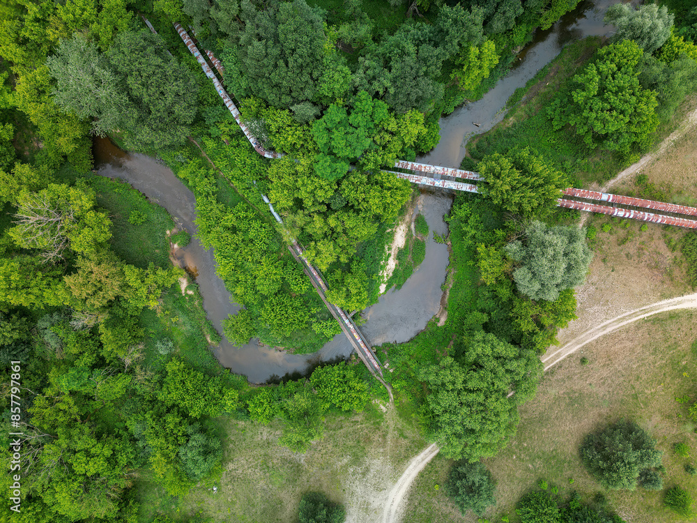 Rusting heating or water supply pipes for an urban agglomeration passing through natural green areas, water management and urban infrastructure, view from above. Rusting heating or water supply pipes for an urban agglomeration passing through natural green areas, water management and urban infrastructure, view from above.