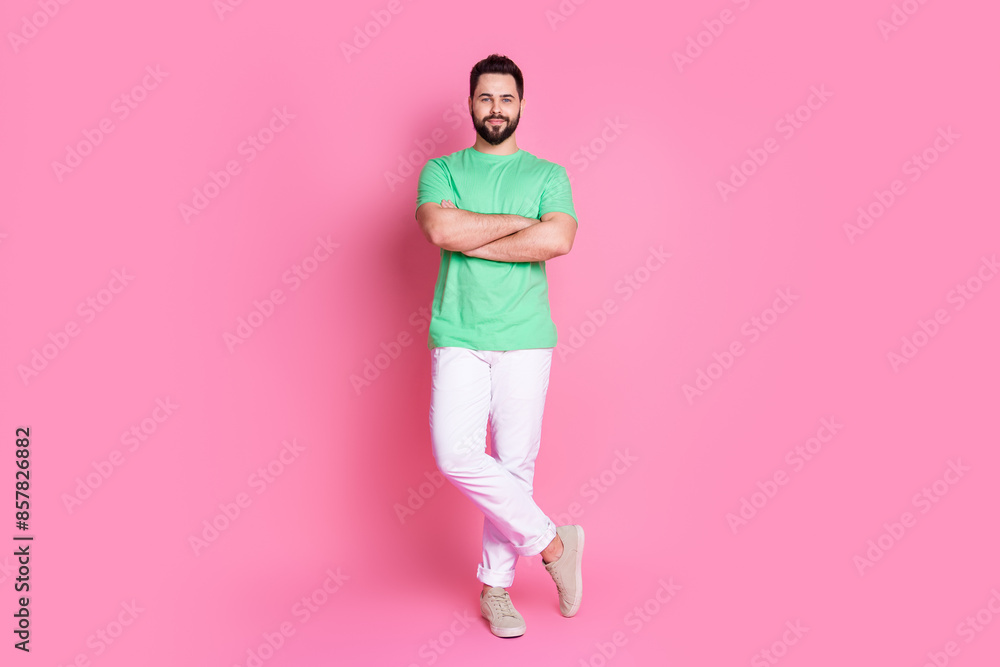 Full size photo of cheerful guy dressed green t-shirt white pants standing holding palms crossed isolated on pink color background Full size photo of cheerful guy dressed green t-shirt white pants standing holding palms crossed isolated on pink color background