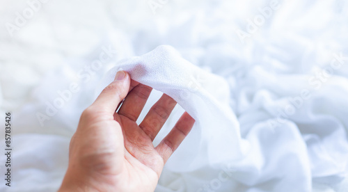 Hand touching cloth. Natural fabric, soft to the touch. Hand holding a white cloth to select. Good fabric.
