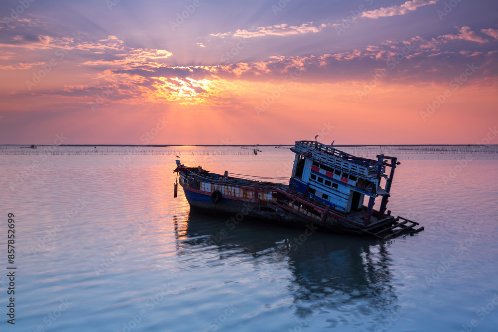 A fishing boat is broken or abandoned in the middle of the sea at sunset in Chonburi, Thailand. A fishing boat is broken or abandoned in the middle of the sea at sunset in Chonburi, Thailand.