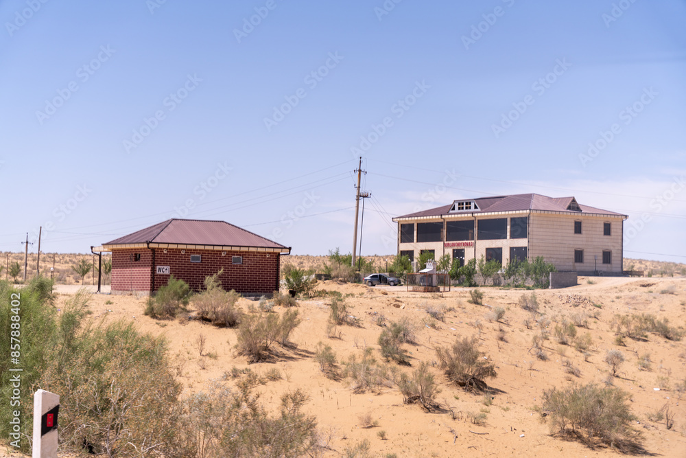A small house is in the middle of a desert. The house is surrounded by a lot of dry grass and dirt A small house is in the middle of a desert. The house is surrounded by a lot of dry grass and dirt