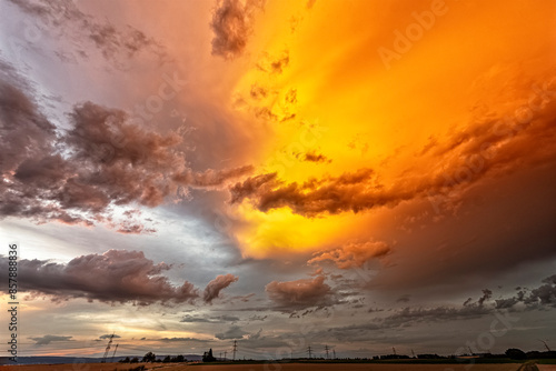 Farbfoto einer abziehenden Gewitterwolke, die vom Licht der untergehenden Sonne orange angestrahlt wird photo