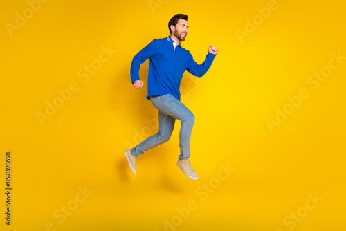 Full length photo of handsome young guy fast running dressed stylish blue garment isolated on yellow color background