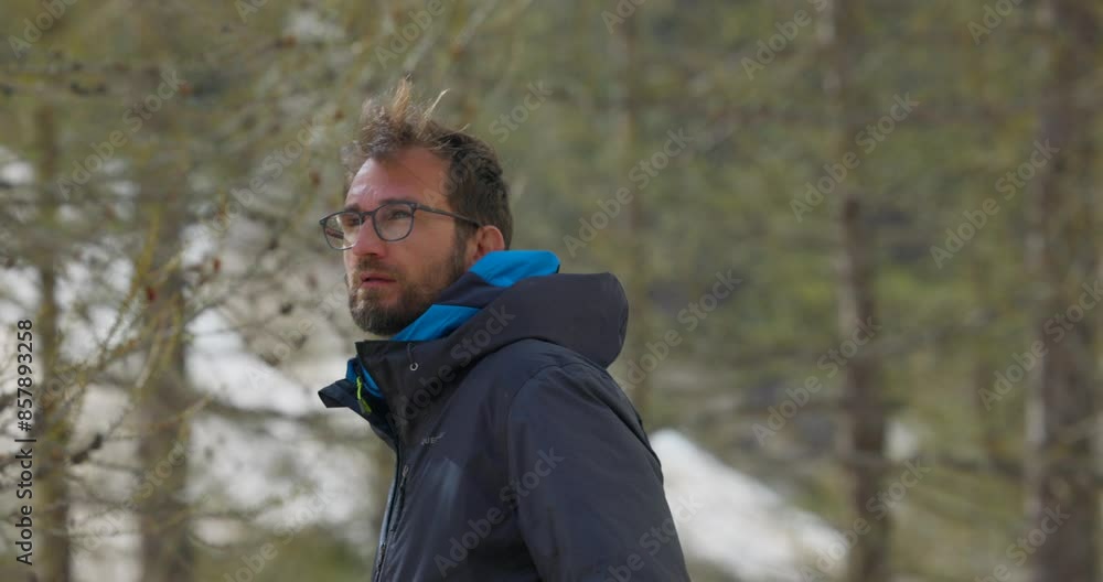 A man wearing a jacket and glasses turns around and looks at the forest A man wearing a jacket and glasses turns around and looks at the forest