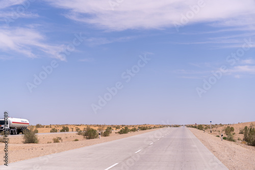 A road with a white truck on it. The sky is blue and there are no clouds