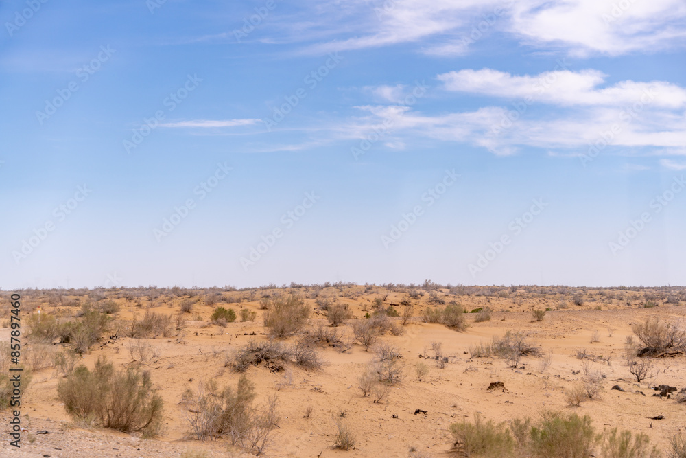 A desert landscape with a clear blue sky. The sky is dotted with clouds, and the sun is shining brightly. The scene is peaceful and serene, with the vast expanse of sand A desert landscape with a clear blue sky. The sky is dotted with clouds, and the sun is shining brightly. The scene is peaceful and serene, with the vast expanse of sand