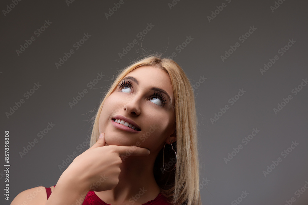 Fototapeta premium Young woman touching chin thinking looking up to empty space bac