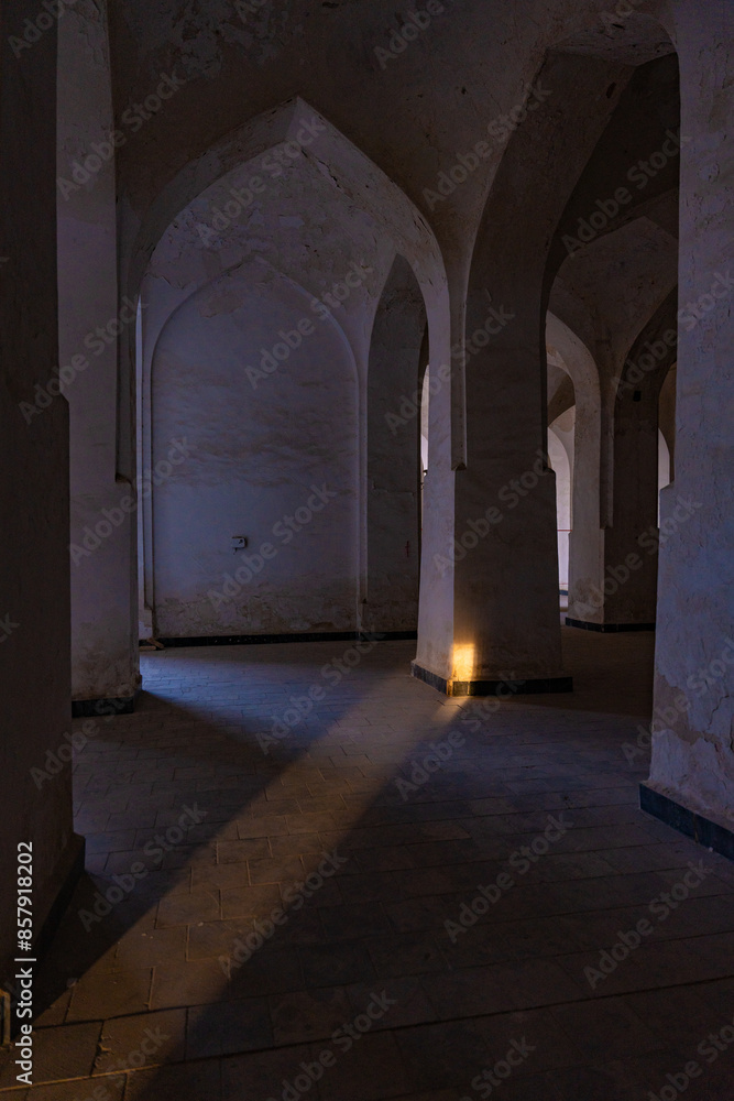 A dark room with a candle in the middle of the floor. The candle is lit and casts a shadow on the floor A dark room with a candle in the middle of the floor. The candle is lit and casts a shadow on the floor