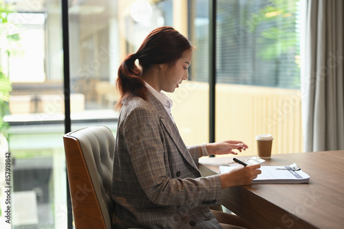 Side view of financial accountant sitting at desk working reviewing financial data or accounting statistics