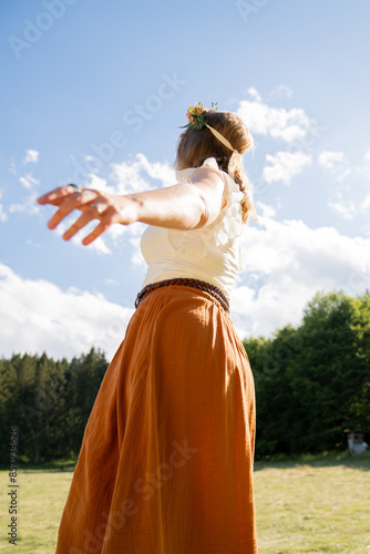 tanzende junge Frau im Sonnenlicht mit langem Rock und Blumen im Haar