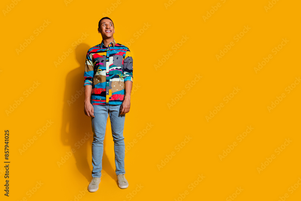 Full size photo of handsome young guy look empty space model wear trendy colorful outfit isolated on yellow color background Full size photo of handsome young guy look empty space model wear trendy colorful outfit isolated on yellow color background
