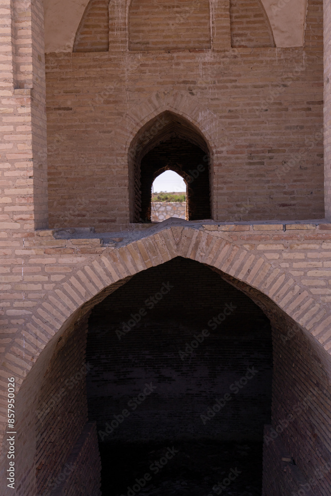 Fototapeta premium A brick archway with a small window in the middle. Scene is somber and mysterious