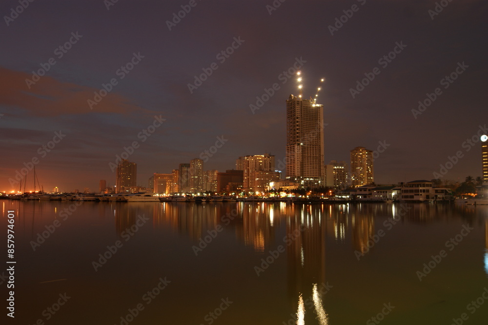 Manila cityscape at night from sea with reflections Manila cityscape at night from sea with reflections