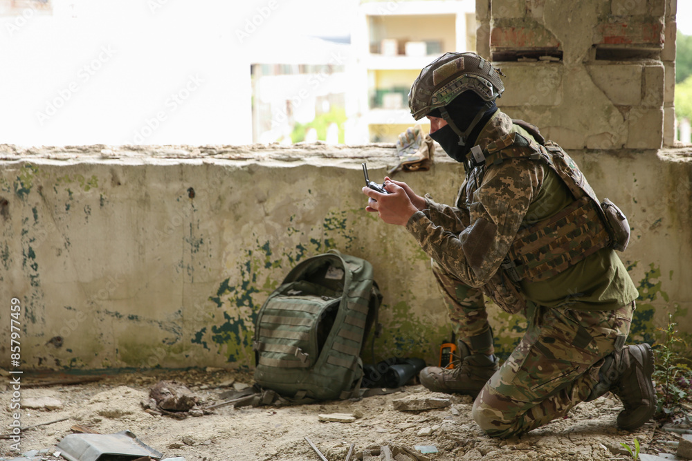 Fototapeta premium Military mission. Soldier in uniform with drone controller inside abandoned building, space for text