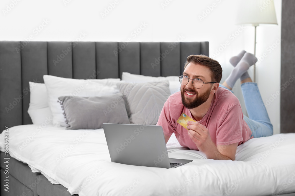 Online banking. Happy young man with credit card and laptop paying purchase at home Online banking. Happy young man with credit card and laptop paying purchase at home