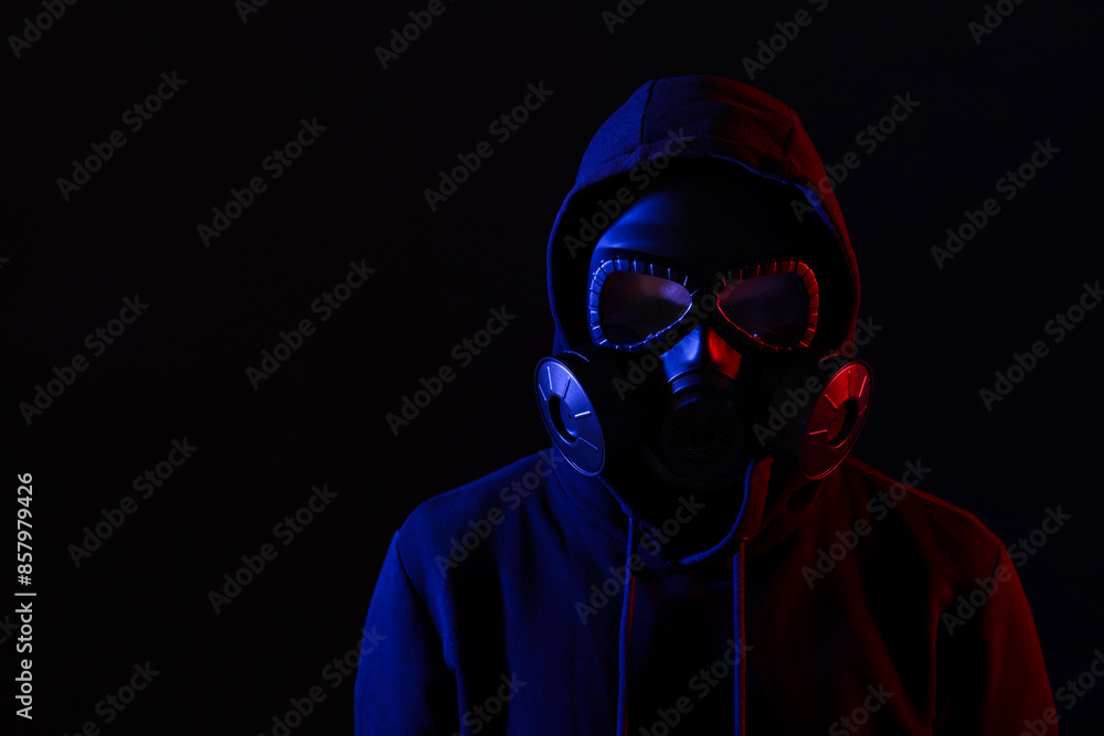 Man wearing gas mask in color lights on black background. Space for text Man wearing gas mask in color lights on black background. Space for text