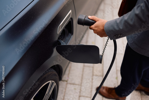 Bilde på lerret Close up of man plugging power cable into hybrid car at charging station