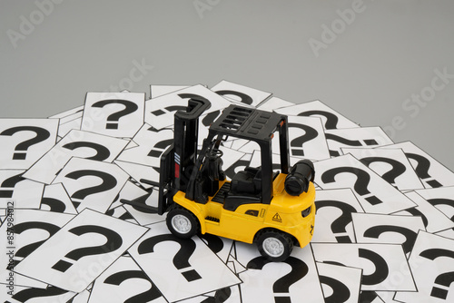 Cargo and logistics FAQ concept. Forklift truck model on many question marks.