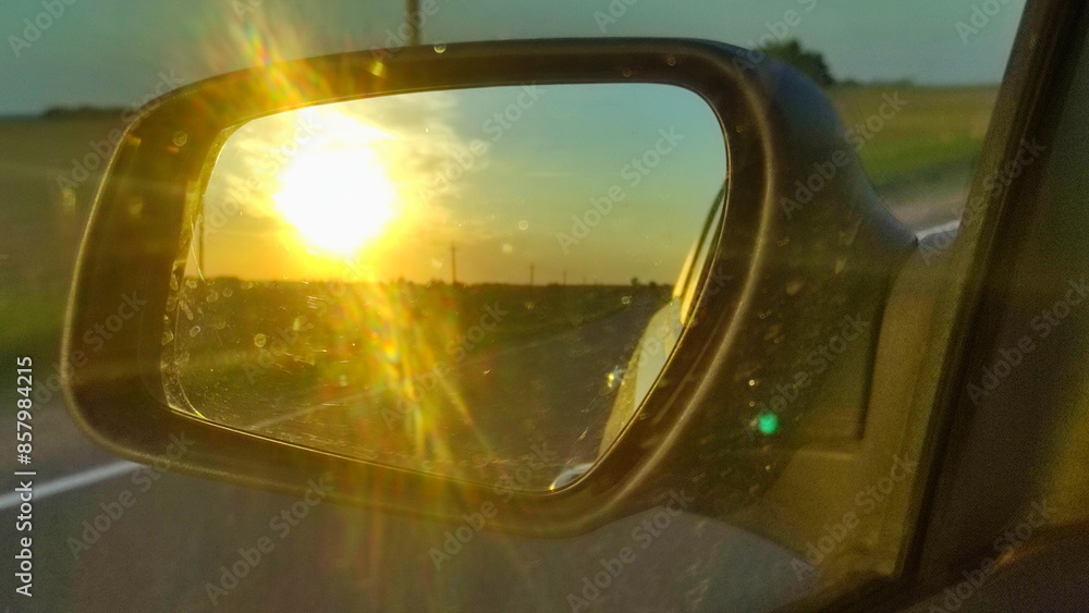 Driving on the road in motion. View of a car mirror on Golden Sunset in Europe
