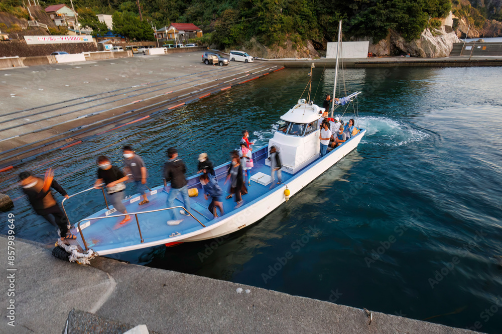 Obraz premium 漁船に乗って、中木沖の太平洋へサンセットクルージングに出航。 日没後の薄明に染まる中木港に無事戻ってきたクルーズ船。日本国静岡県伊豆半島賀茂郡南伊豆町中木から渡し船で渡るヒリゾ浜にて。 2022年10月撮影。 