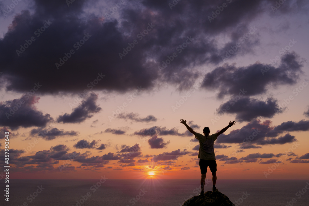 Man at sunset. Man with arms up at sunset in front of the sea.