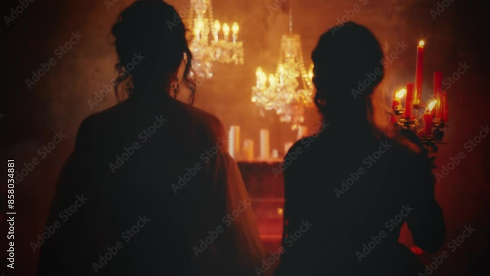 two women vintage clothes white red dress. Fantasy beauty Sexy girl walking in night dark room hand holding old style candlestick candles burning light back rear view. Gothic Mystery woman queen. 4k.