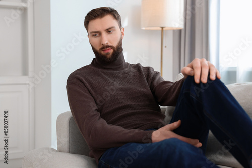 Loneliness concept. Sad man sitting on sofa at home