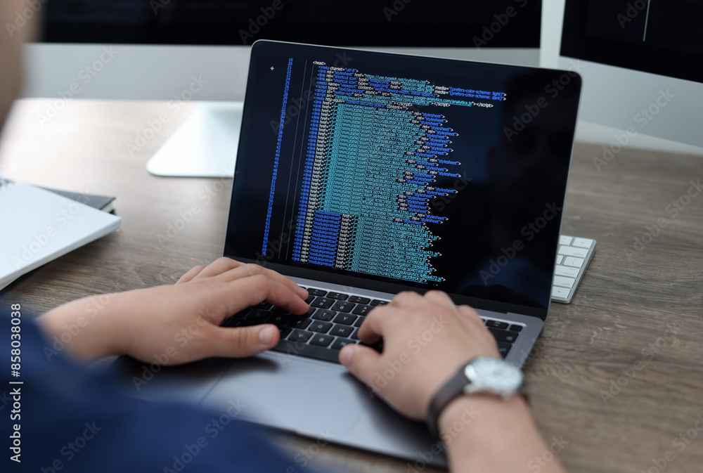 Programmer working with laptop at desk in office, closeup Programmer working with laptop at desk in office, closeup