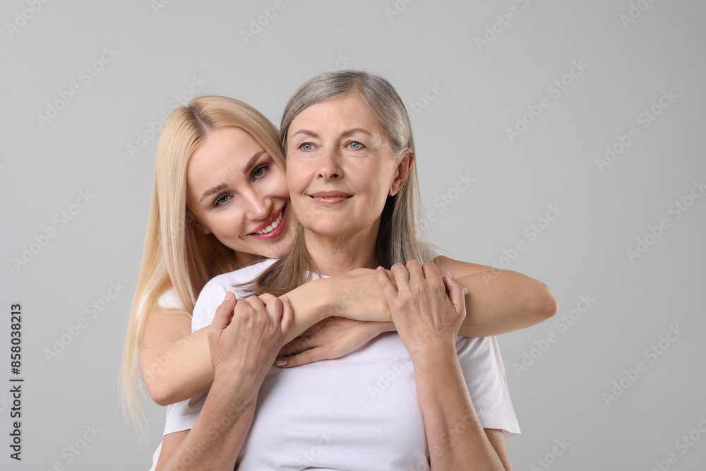 Family portrait of young woman and her mother on light grey background Family portrait of young woman and her mother on light grey background
