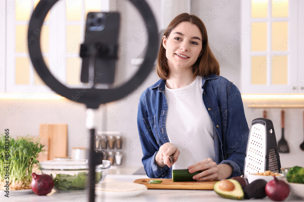 Food blogger cooking while recording video with smartphone and ring lamp in kitchen Food blogger cooking while recording video with smartphone and ring lamp in kitchen
