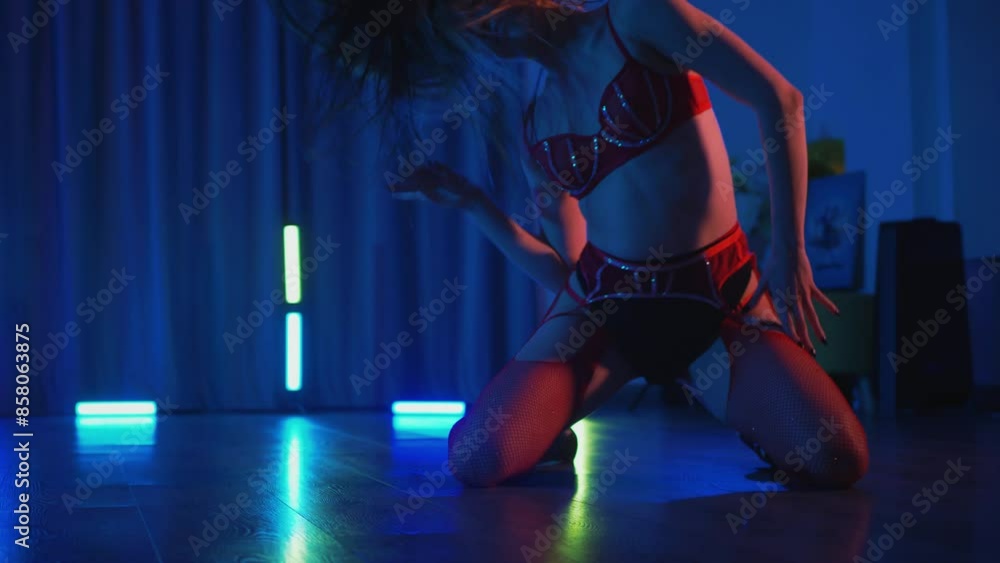Young woman in red lingerie erotically dancing twerk and high heels. Half-shaven Girl in black shorts moving seductively gracefully in darkened space. Striptease in a disco club on stage. Young woman in red lingerie erotically dancing twerk and high heels. Half-shaven Girl in black shorts moving seductively gracefully in darkened space. Striptease in a disco club on stage.
