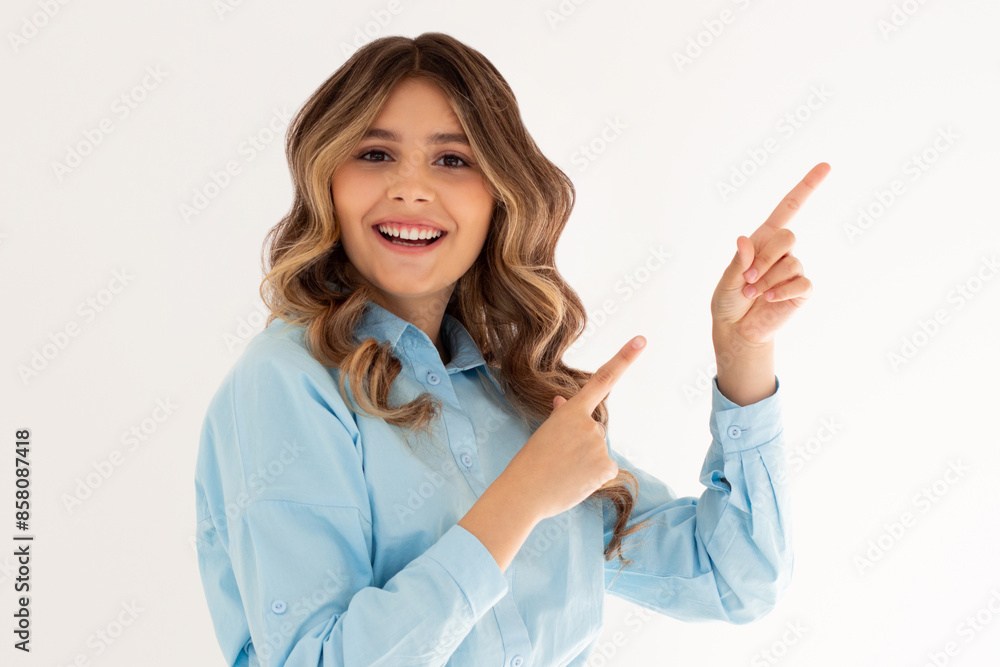 Young confident woman showing logo on empty space. Smiling girl inviting or advertising promo deal, pointing fingers right and looking at camera, white background. Young confident woman showing logo on empty space. Smiling girl inviting or advertising promo deal, pointing fingers right and looking at camera, white background.