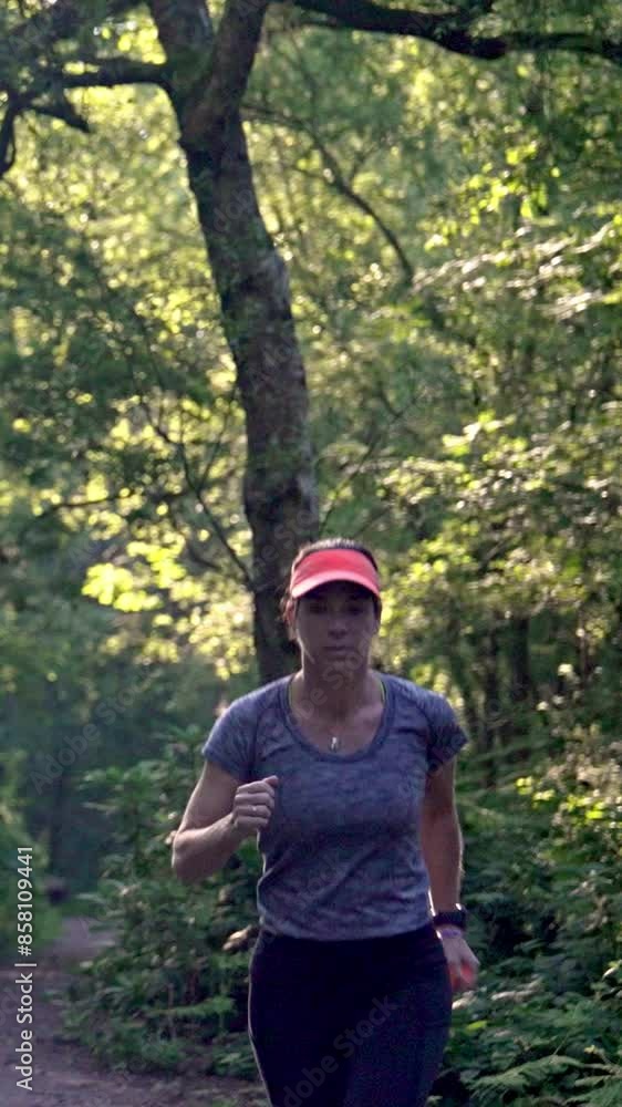 Woman running in forest - woods workout - vertical runner Woman running in forest - woods workout - vertical runner
