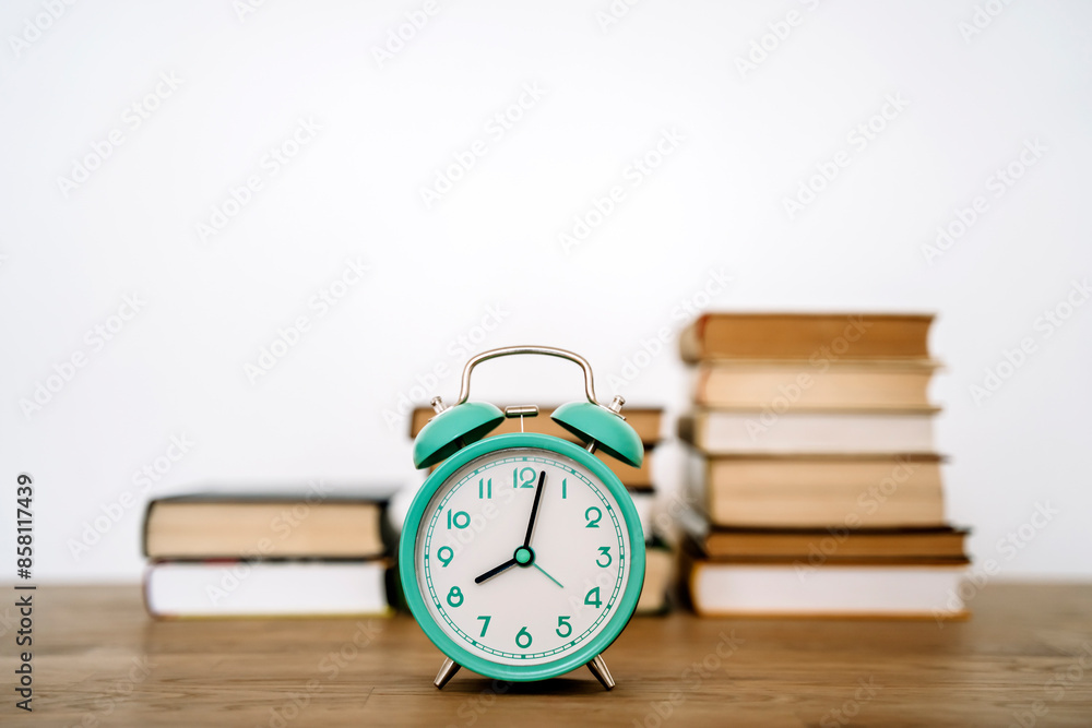 Books and alarm clock on a desk in a school or university classroom. Education, study concept background Books and alarm clock on a desk in a school or university classroom. Education, study concept background