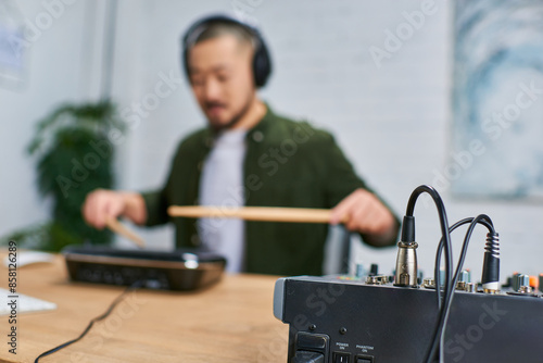 An Asian man in casual attire plays music in a studio. photo