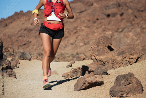 Fotografie Female athlete run mountain race with hydratation trail vest for running