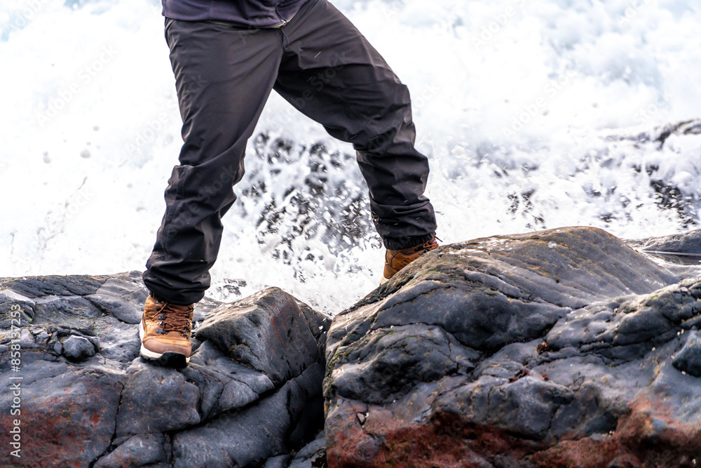 A person is standing on a rock near a body of water A person is standing on a rock near a body of water