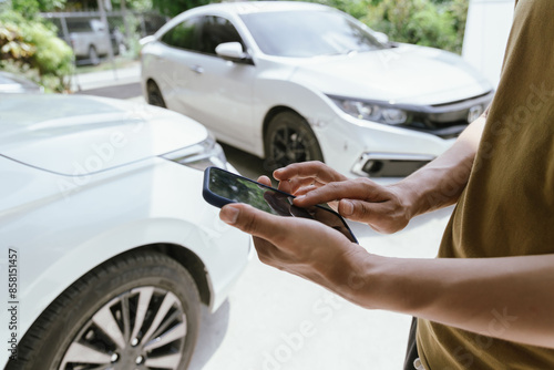 Foto A young adult man, holding a smartphone, takes a photo of his dented car after an accident