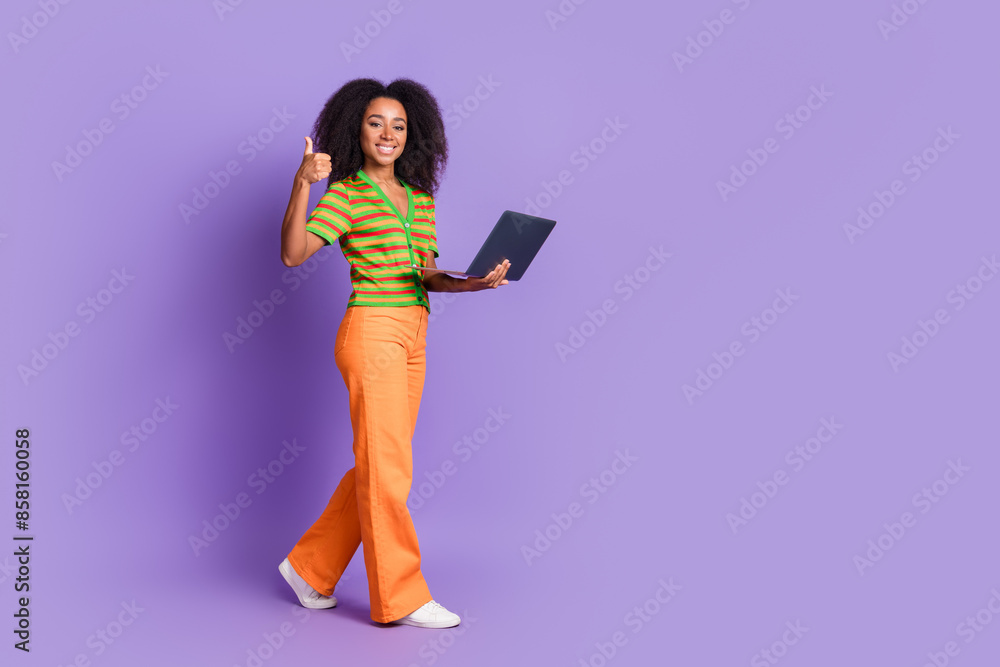 Full length photo of cheerful pretty lady dressed striped cardigan showing thumb up typing gadget empty space isolated purple color background Full length photo of cheerful pretty lady dressed striped cardigan showing thumb up typing gadget empty space isolated purple color background