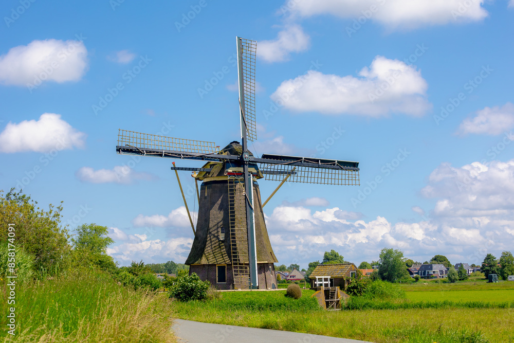 Spring landscape view with beautiful traditional windmill under blue sky, Dutch agriculture in countryside with corn or maize field along the Vecht river, Nigtevecht, Province of Utrecht, Netherlands.