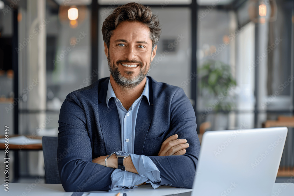 Stylish confident businessman smiling at modern office desk with laptop Stylish confident businessman smiling at modern office desk with laptop