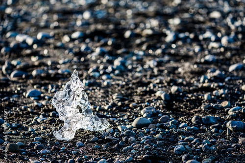 Almost as silver jewelry. Ice imaginarium. Icy  particles and pieces on the black wet volcanic pebbles beach called Diamond Beach. Eastern Iceland, Europe photo