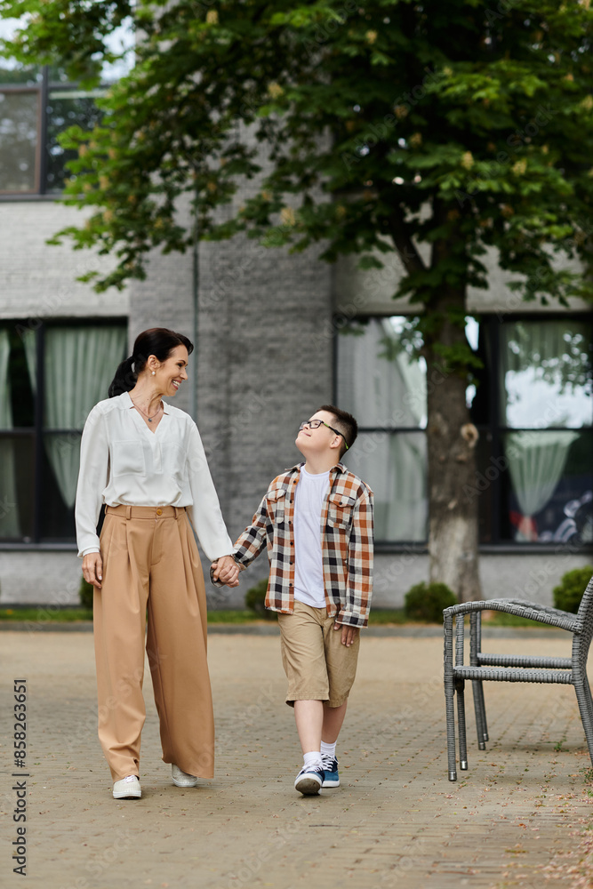 A mother walks hand-in-hand with her son, who has Down syndrome, near an office building. A mother walks hand-in-hand with her son, who has Down syndrome, near an office building.