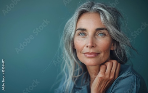 A woman with gray hair and blue eyes is smiling. She is wearing a blue shirt and has her hand on her neck © imagineRbc