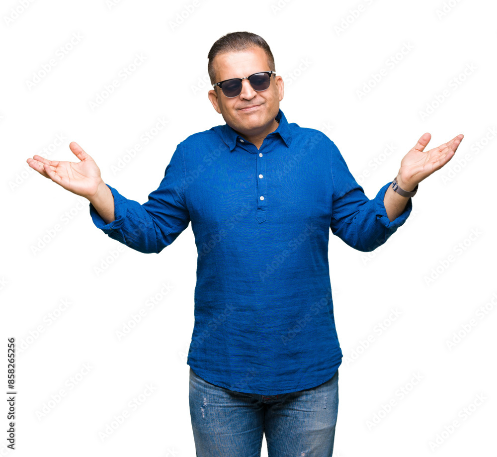 Middle age arab man wearing sunglasses over isolated background clueless and confused expression with arms and hands raised. Doubt concept. Middle age arab man wearing sunglasses over isolated background clueless and confused expression with arms and hands raised. Doubt concept.