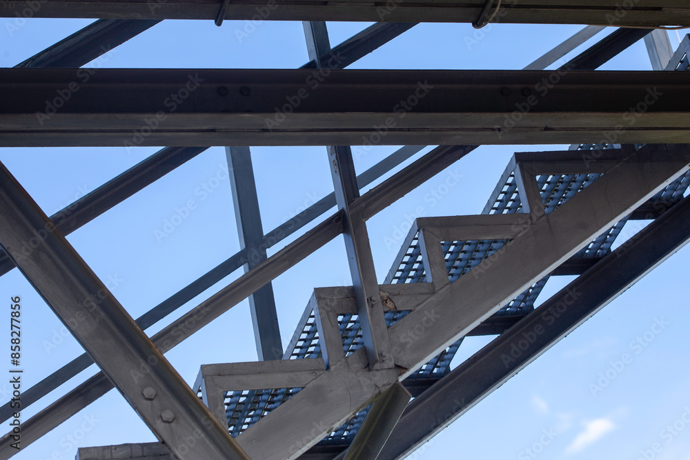 Iron staircase for up to maintenance work. Steel framing and beams structural elements against blue sky Iron staircase for up to maintenance work. Steel framing and beams structural elements against blue sky