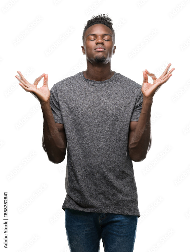 Young african american man wearing grey t-shirt relax and smiling with eyes closed doing meditation gesture with fingers. Yoga concept. Young african american man wearing grey t-shirt relax and smiling with eyes closed doing meditation gesture with fingers. Yoga concept.