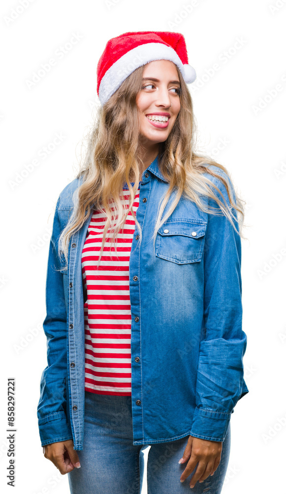 Beautiful young blonde woman wearing christmas hat over isolated background looking away to side with smile on face, natural expression. Laughing confident. Beautiful young blonde woman wearing christmas hat over isolated background looking away to side with smile on face, natural expression. Laughing confident.