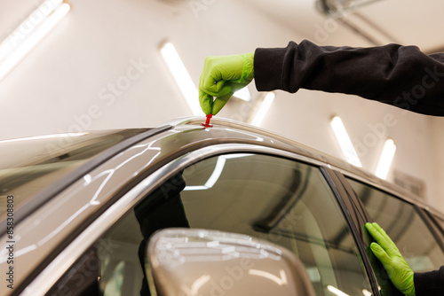 Person in green gloves repairing vehicle, working on car hood